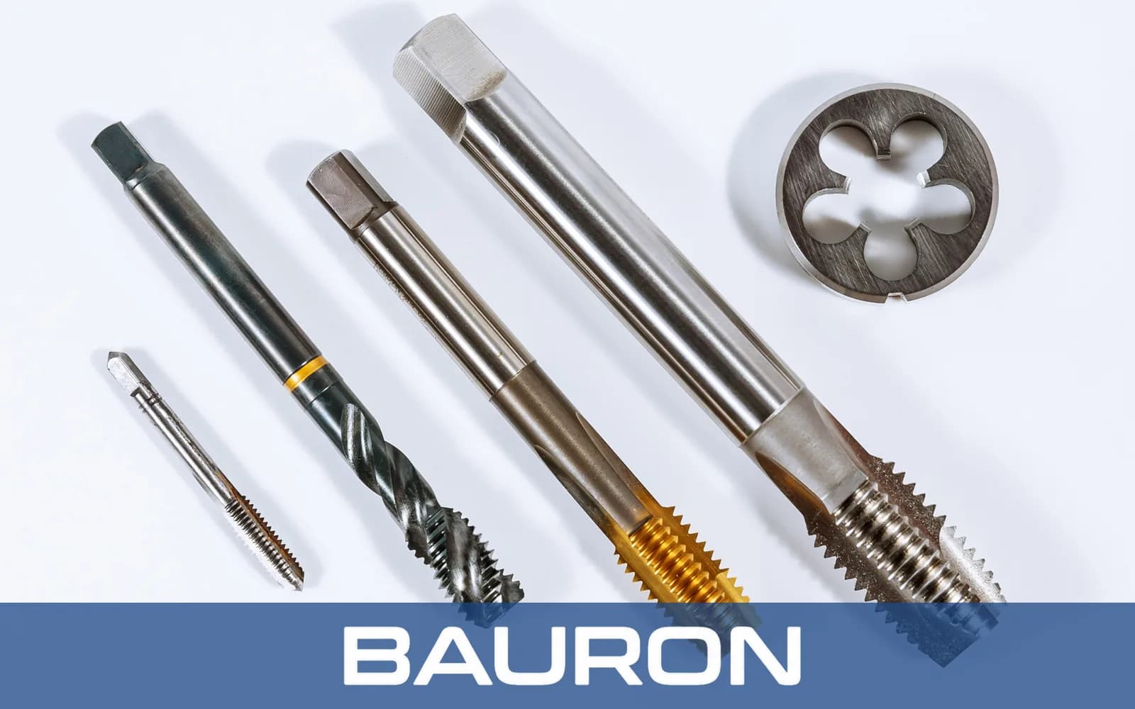 Tarauds à main et tarauds machine de plusieurs tailles à côté d'une filière ronde